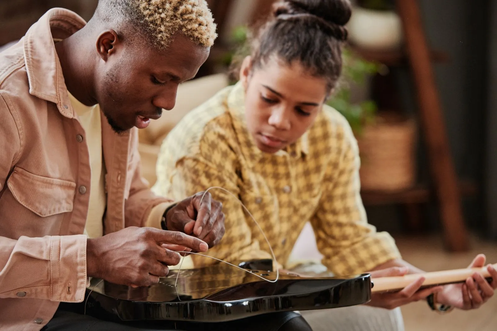 Father teaching daughter to fix guitar strings at home, bonding over music.